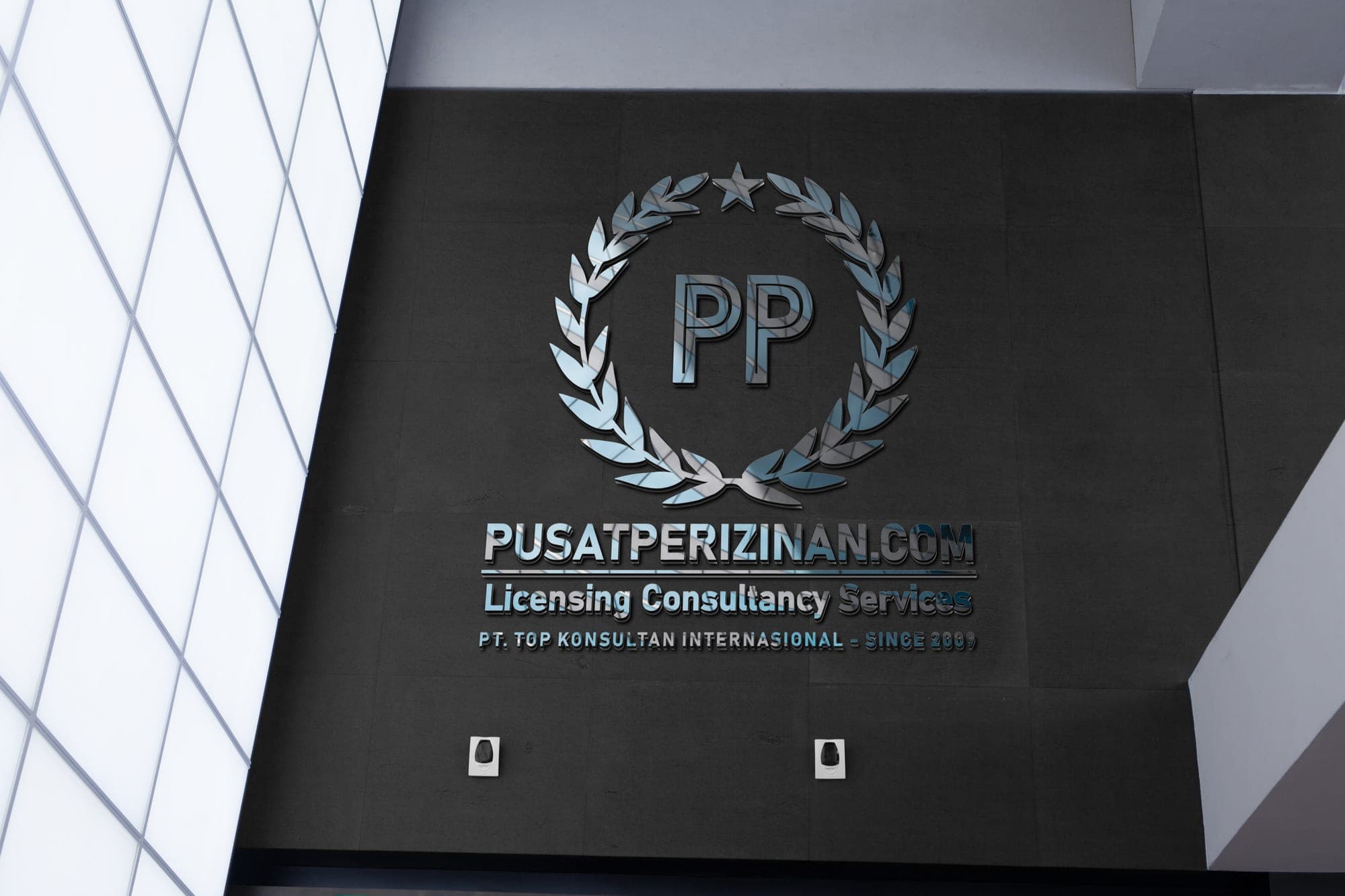 Dinding branding PusatPerizinan.com — logo PP metalik pada dinding gelap ruang kantor